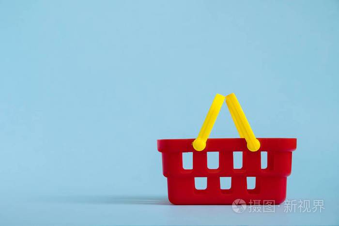 蓝色背景上隔离的红色空玩具塑料购物篮销售和购物概念复制空间